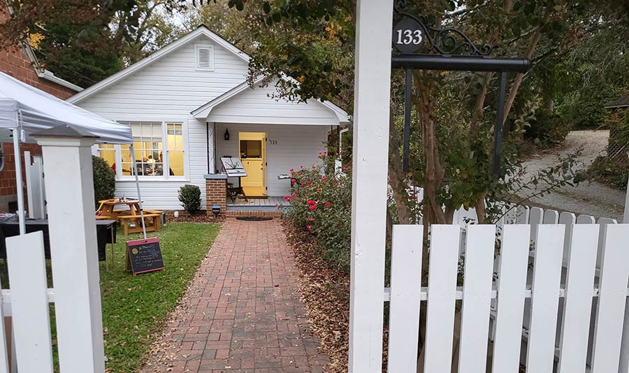 Photo of a little white house with a picket fence