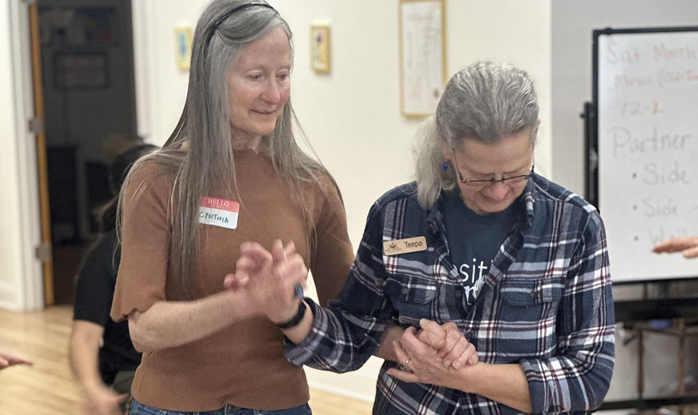 Photo of Teepa Snow walking with a woman, guiding her with her hands