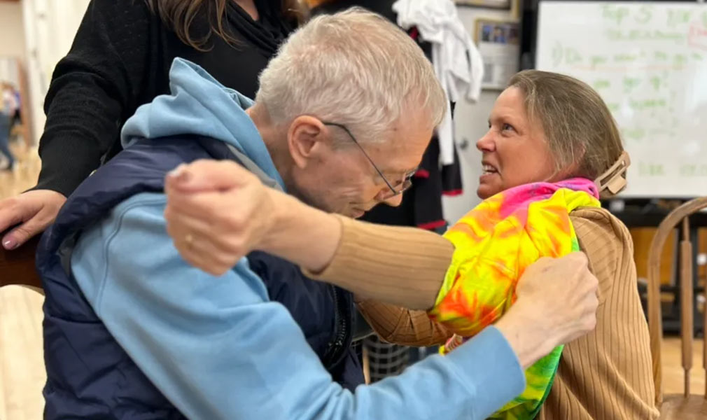 Photo of a man helping a woman put on a shirt